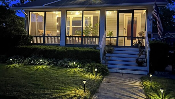 A two-story house with a front porch, a small front yard, and a driveway.