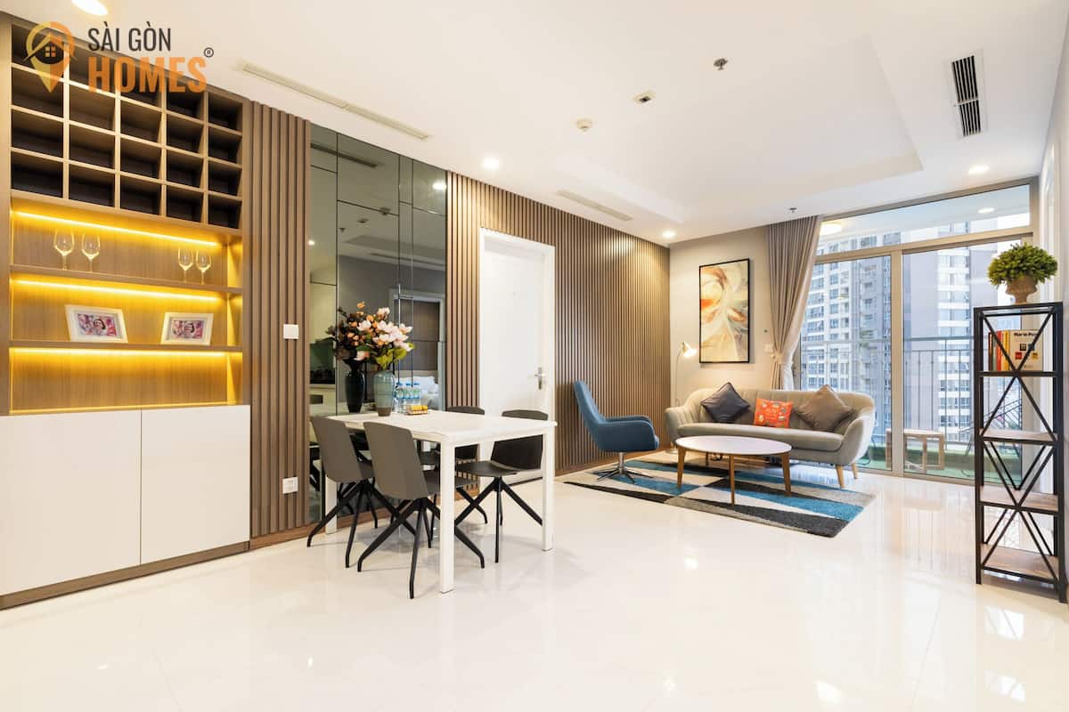 A modern living room with a dining area, a sofa, and a coffee table. There is a large window providing a view of the city.
