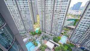 A high-rise residential building with multiple balconies, a central courtyard with a swimming pool, and surrounding greenery. - Landmark 81 Luxury - SaigonHomes (Ho Chi Minh City)