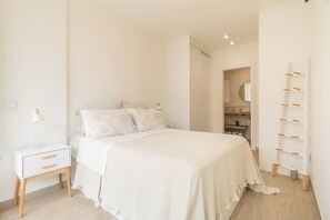 A minimalist bedroom with a bed, bedside table, and a wall-mounted shelf. - House Viñol 24 Las Canteras Beach (Palmas De Gran Canaria, Las)