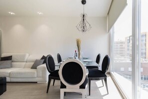 A modern dining area with a white table, black chairs, and a chandelier. - House Viñol 24 Las Canteras Beach (Palmas De Gran Canaria, Las)