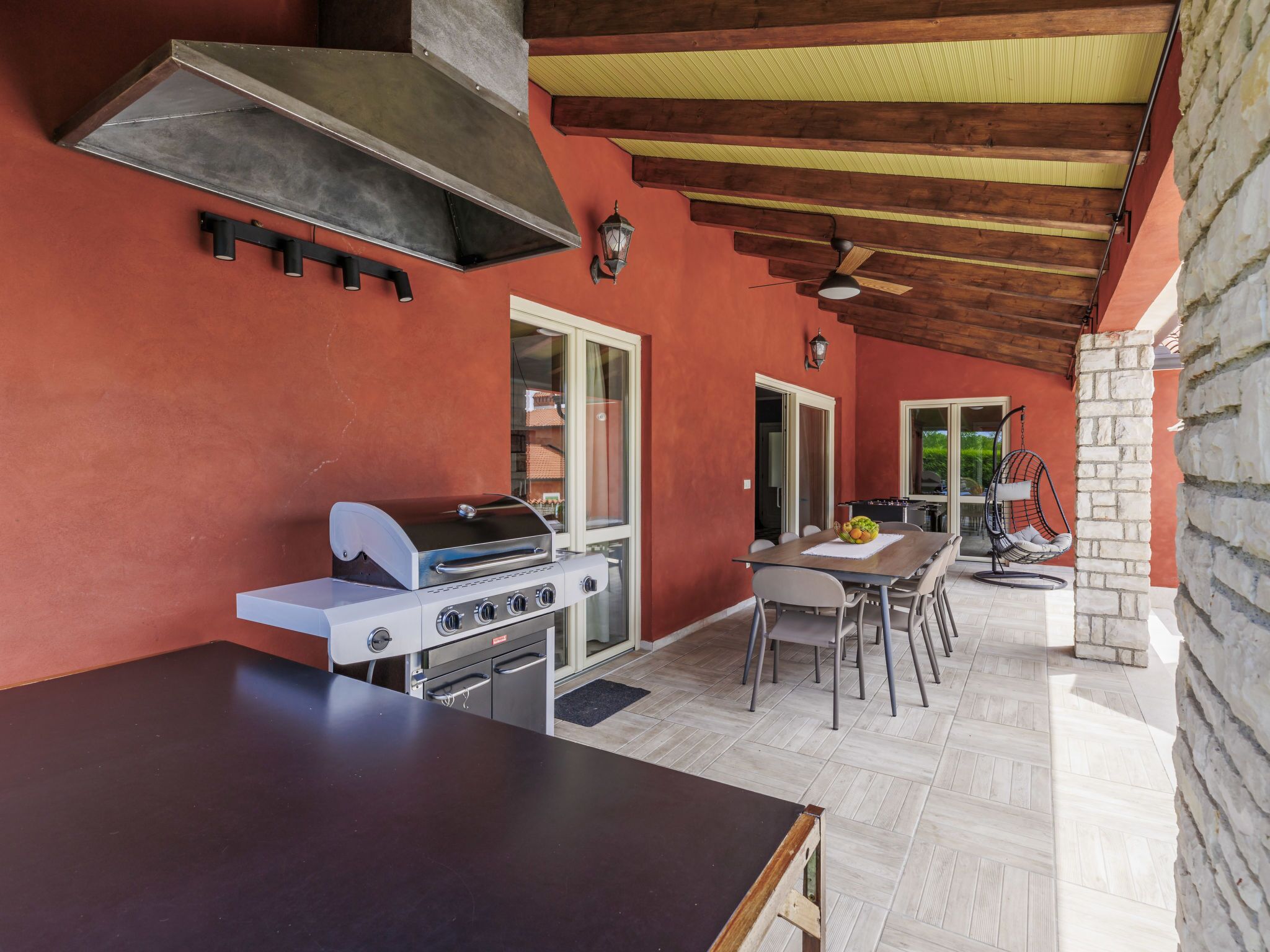 Una cocina al aire libre con una parrilla, una mesa y sillas.