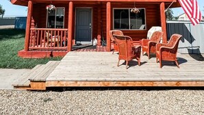 Une cabane en rondins à deux étages, dotée d’un balcon, d’une terrasse avec des fauteuils en osier et d’un drapeau américain.