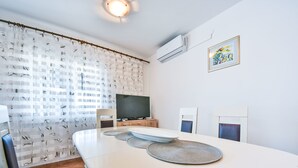 A modern dining area with a round table, chairs, a television, and a patterned curtain. - Maldini by Interhome (Zadar/Sukošan)
