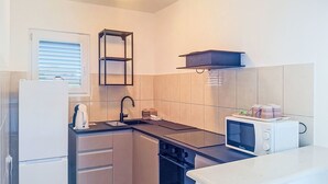 A compact kitchen with a refrigerator, stove, microwave, and a small sink. - Maldini by Interhome (Zadar/Sukošan)