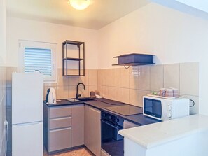 Une cuisine de taille réduite équipée d’un réfrigérateur, d’une cuisinière, d’un four à micro-ondes et d’un petit évier.