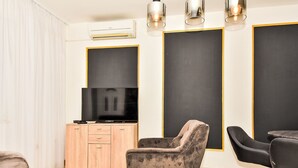 Een moderne woonkamer met een flatscreen televisie, een houten kast en twee fauteuils.