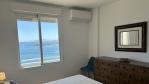 A bedroom with a bed, a dresser, a chair, and a large window with a view of the sea. - DELICIAS PLAYA, beachfront with parking included (Aguilas)