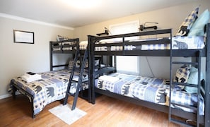 Habitación con literas, una escalera, un cuadro en la pared y una ventana con persianas.