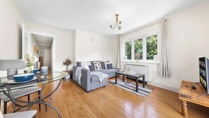 Ein modernes Wohnzimmer mit einem Glastisch, einem grauen Sofa und einem Holztisch.