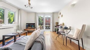 Ein modernes Wohnzimmer mit Sofa, Couchtisch, Fernseher und einem Essbereich mit Stühlen und Tisch.