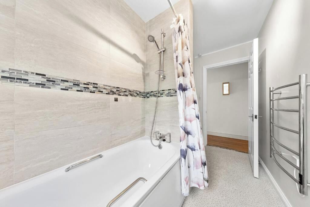 Un baño moderno con bañera, ducha y zona de ducha con mampara de vidrio.