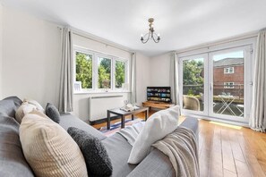 Un salon moderne avec un canapé gris, un téléviseur à écran plat et un coin repas comprenant une table et des chaises.