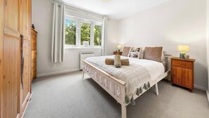 Ein Schlafzimmer mit Bett, Nachttischen, einem Kleiderschrank, einem Fenster und einer Pendelleuchte.