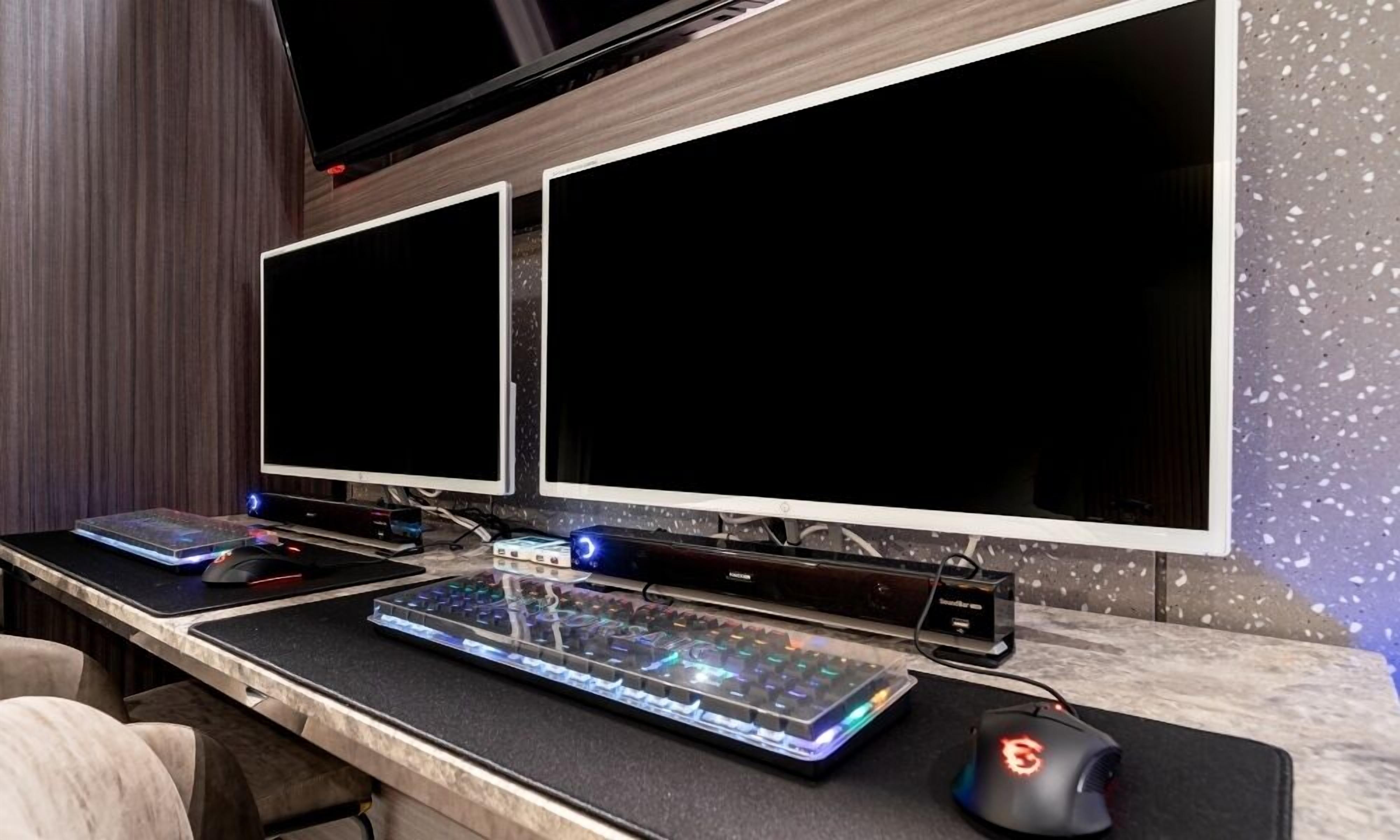 Un espace de jeu équipé de deux écrans, d’un clavier mécanique et d’une souris de jeu, le tout posé sur un bureau en marbre.