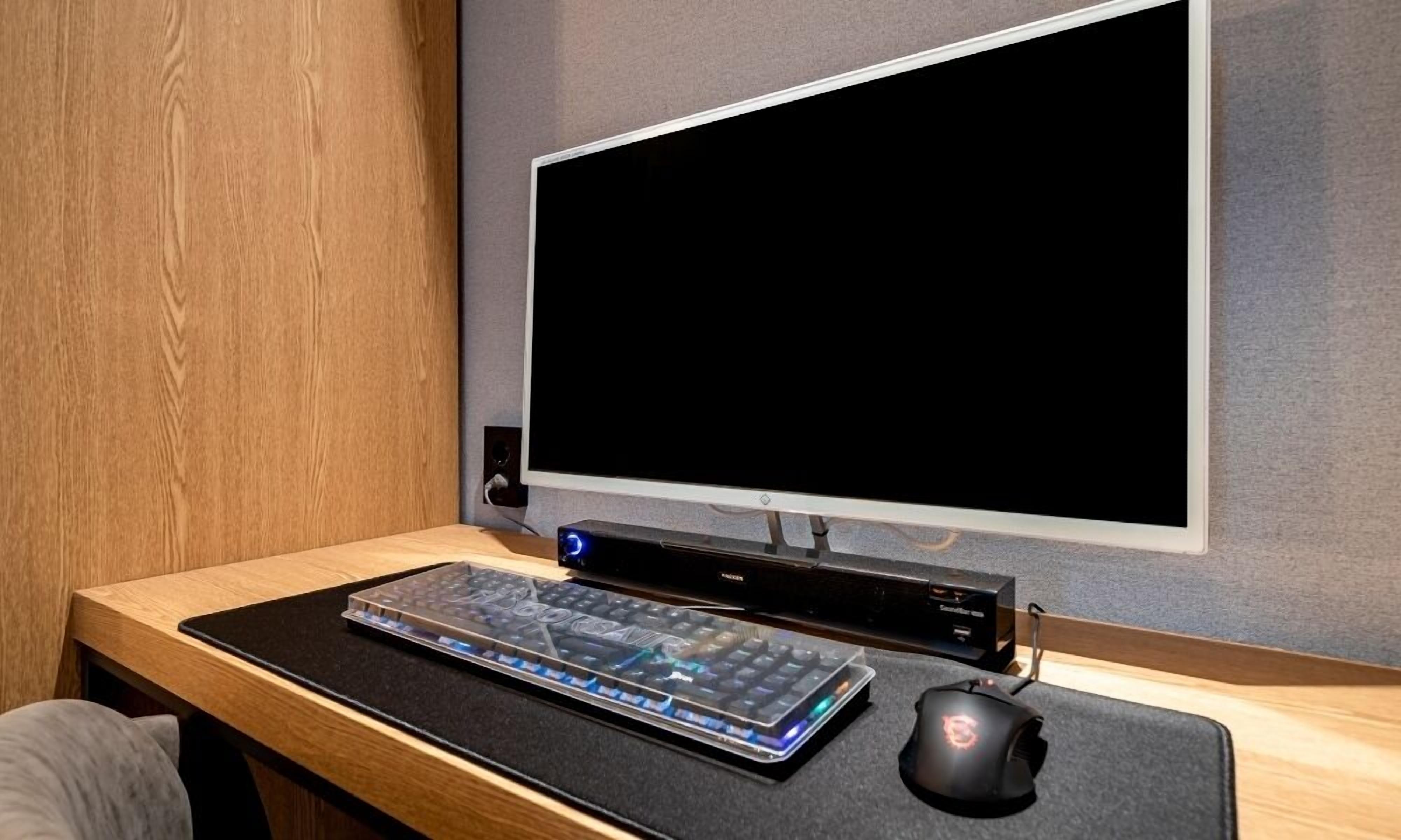 A modern office setup with a large monitor, keyboard, and mouse on a wooden desk.