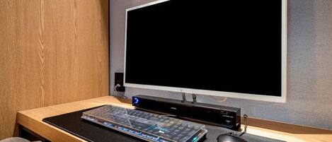 A modern office setup with a large monitor, keyboard, and mouse on a wooden desk.