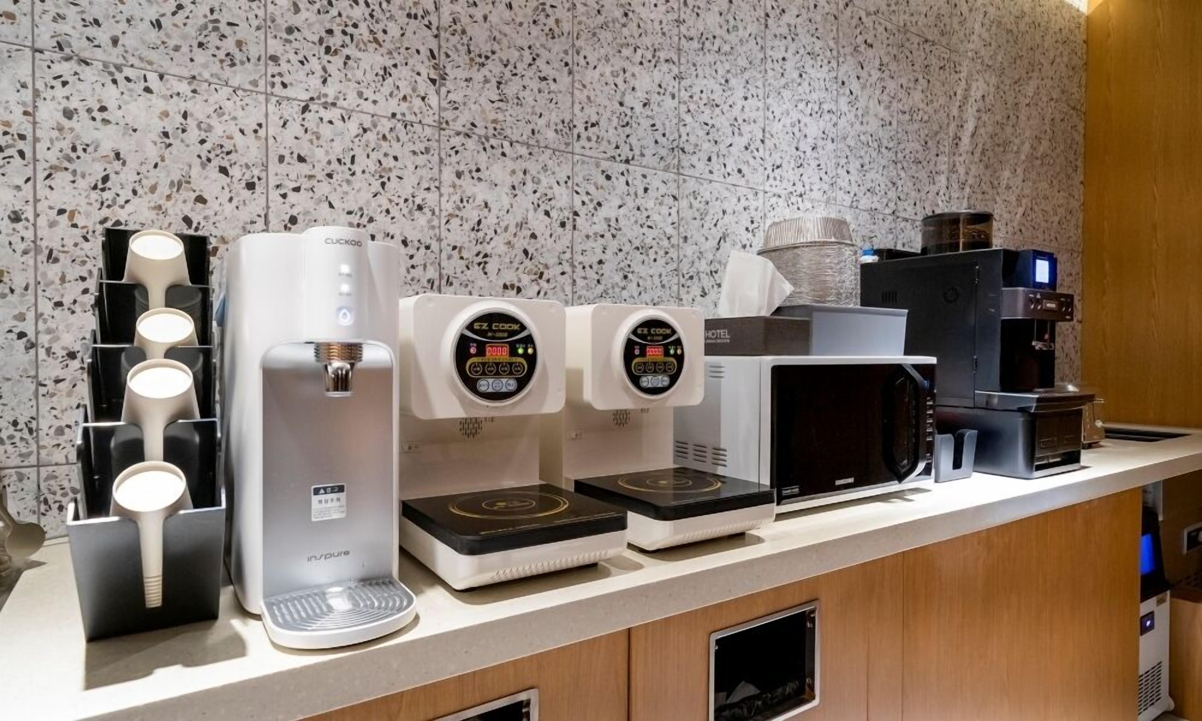 Una estación de café con varias máquinas de café y un microondas.