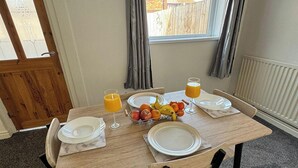 Een ontbijttafel gedekt met borden, glazen sinaasappelsap en een schaal fruit.