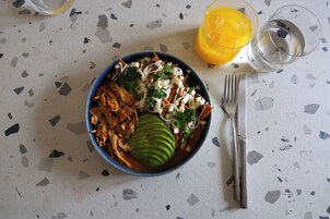 Un plato de comida con un tenedor y un cuchillo a un lado, sobre una superficie moteada.