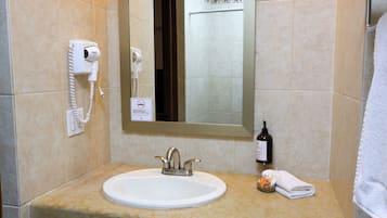 Une salle de bain équipée d’un lavabo, d’un sèche-cheveux, d’un savon liquide et d’une serviette.