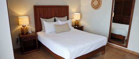 A neatly made bed with a wooden headboard, two bedside tables with lamps, and a mirror on the wall.