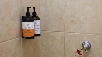 Een badkamer met twee flessen Vervan shampoo en een warmwaterkraan.
