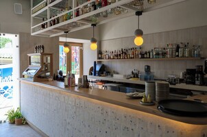 Zona de bar con mostrador, estanterías con botellas y luces colgantes.