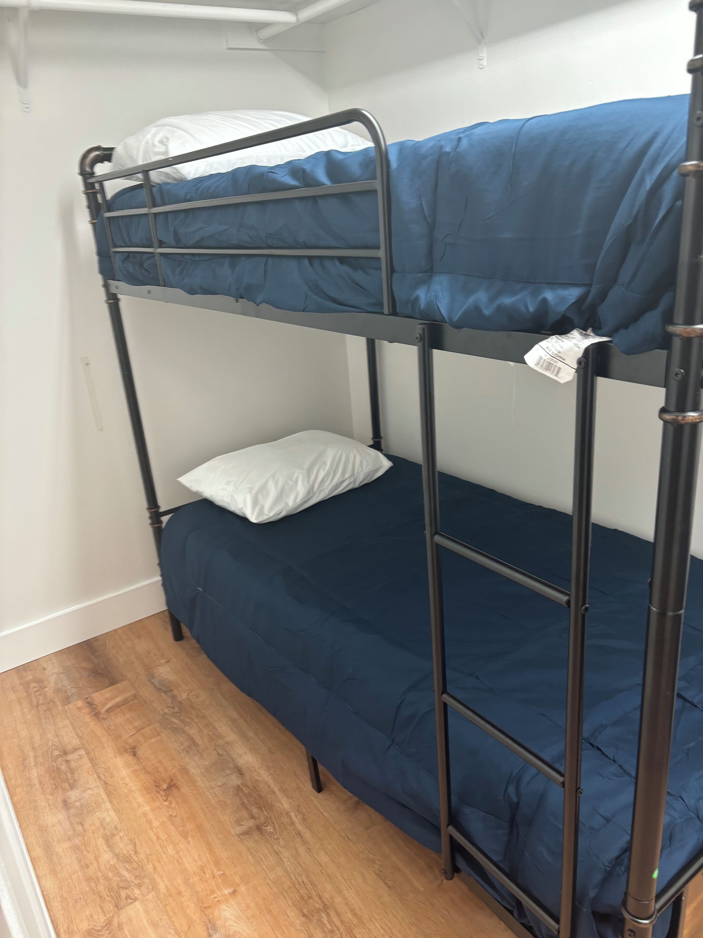 Uma cama beliche com roupa de cama azul e travesseiro branco.