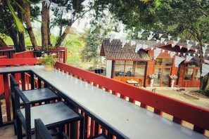 A restaurant with outdoor seating, red railings, and a small building with a tiled roof. - Inthawa Resort (Feuang, Laos) (Vientiane)