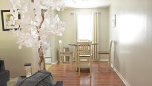 Un comedor con una mesa y sillas de madera, una planta en maceta y una ventana con cortinas.