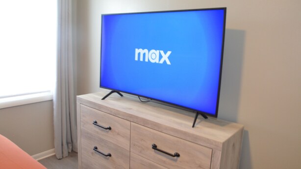 Un televisor sobre un mueble de madera con una pantalla azul que muestra la palabra "max".