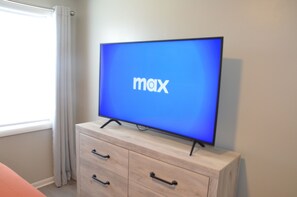 Uma televisão sobre um móvel de madeira, com a tela azul exibindo a palavra "max".