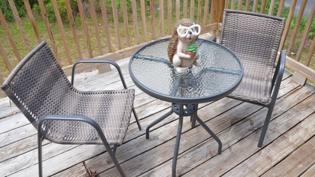A wooden deck with a glass table and two wicker chairs. - The Perfect Spot: 2-Bedroom Apt - Centrally located in fabulous Enterprise!  (Enterprise)