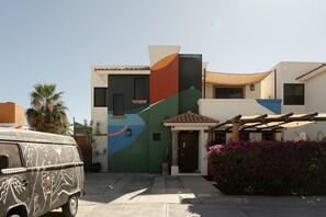 A modern house with a colorful facade, a car parked in front, and a pergola with purple flowers. - Casa Alonso | Spacious House with Private Courtyard in San Jose (San José del Cabo)