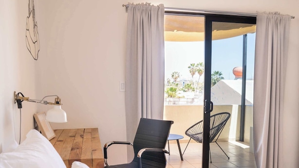 Ein Hotelzimmer mit Bett, Schreibtisch, Stuhl und Blick ins Freie.