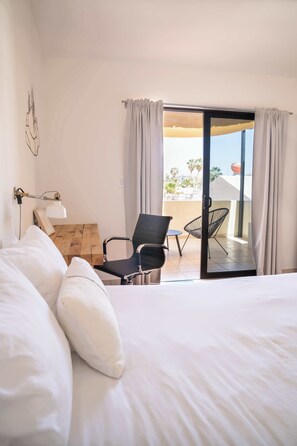 Quarto de hotel com uma cama, uma escrivaninha, uma cadeira e vista para o exterior.