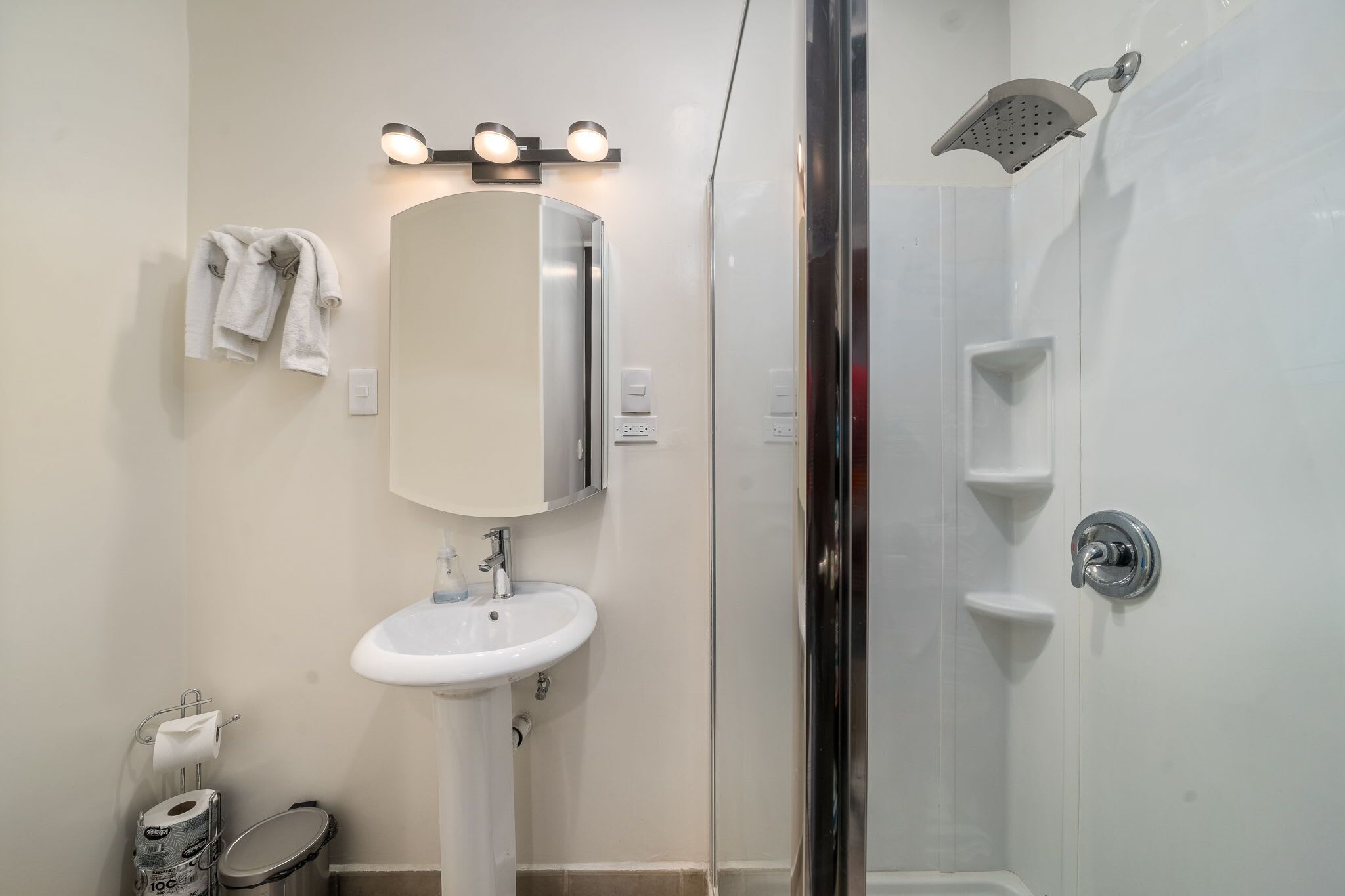 Une salle de bain avec un lavabo blanc, un miroir et une douche.