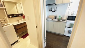 Une cuisine de taille réduite avec des meubles blancs, un four à micro-ondes et un évier.