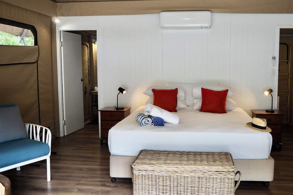 Ein geräumiges Schlafzimmer mit einem großen Bett, zwei Nachttischen, einem Sessel und einer Korbschaukel.
