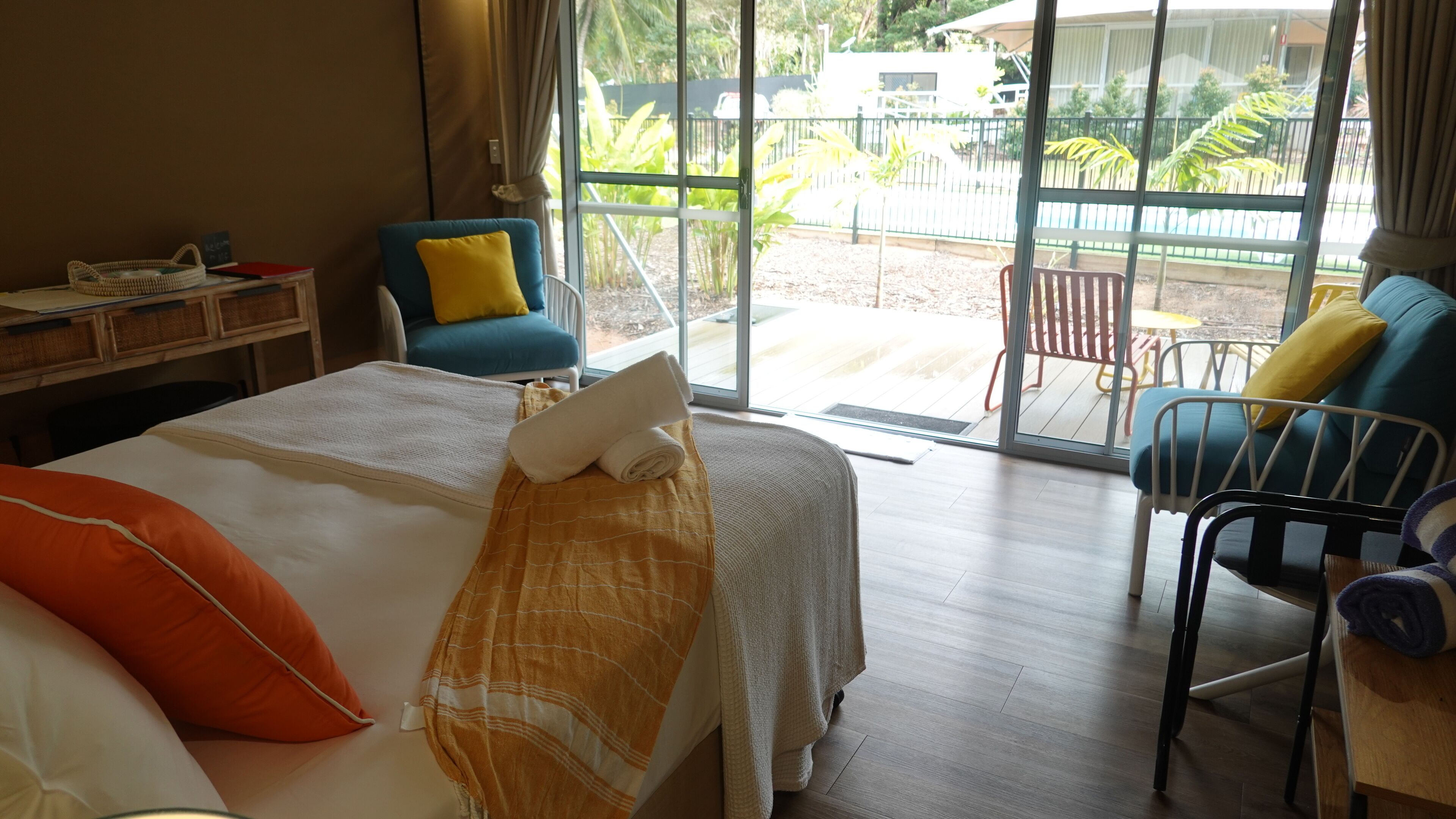 Quarto de hotel com cama, escrivaninha, cadeira e vista para o exterior.