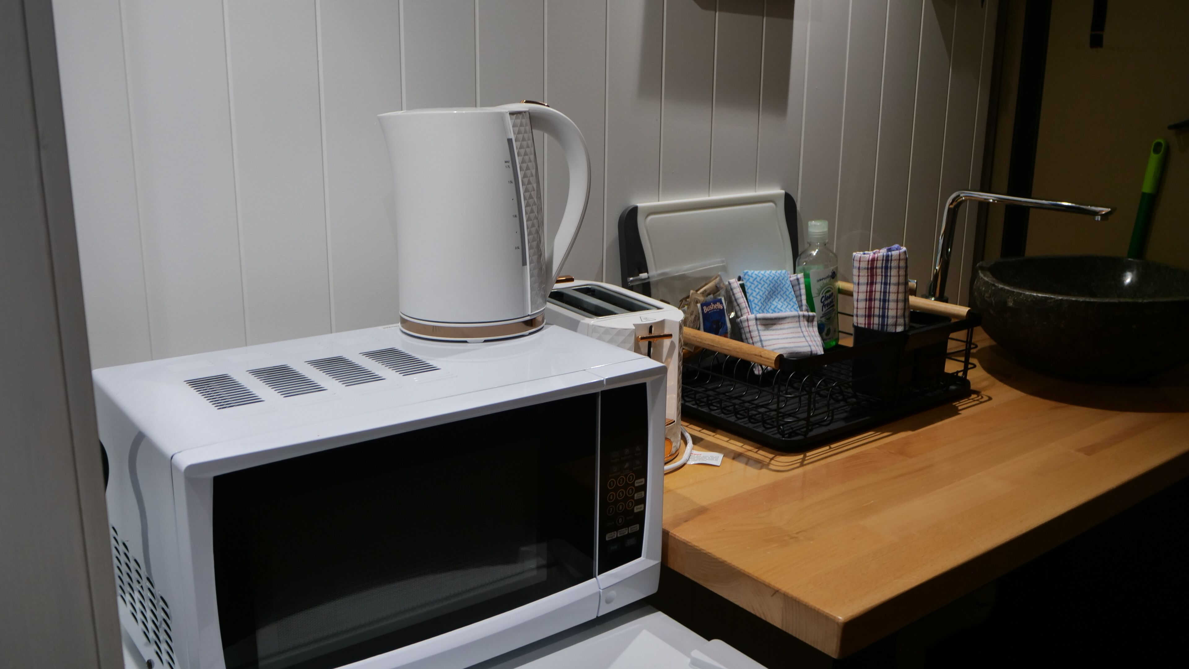 Een keuken met een magnetron, broodrooster en waterkoker op het aanrecht.