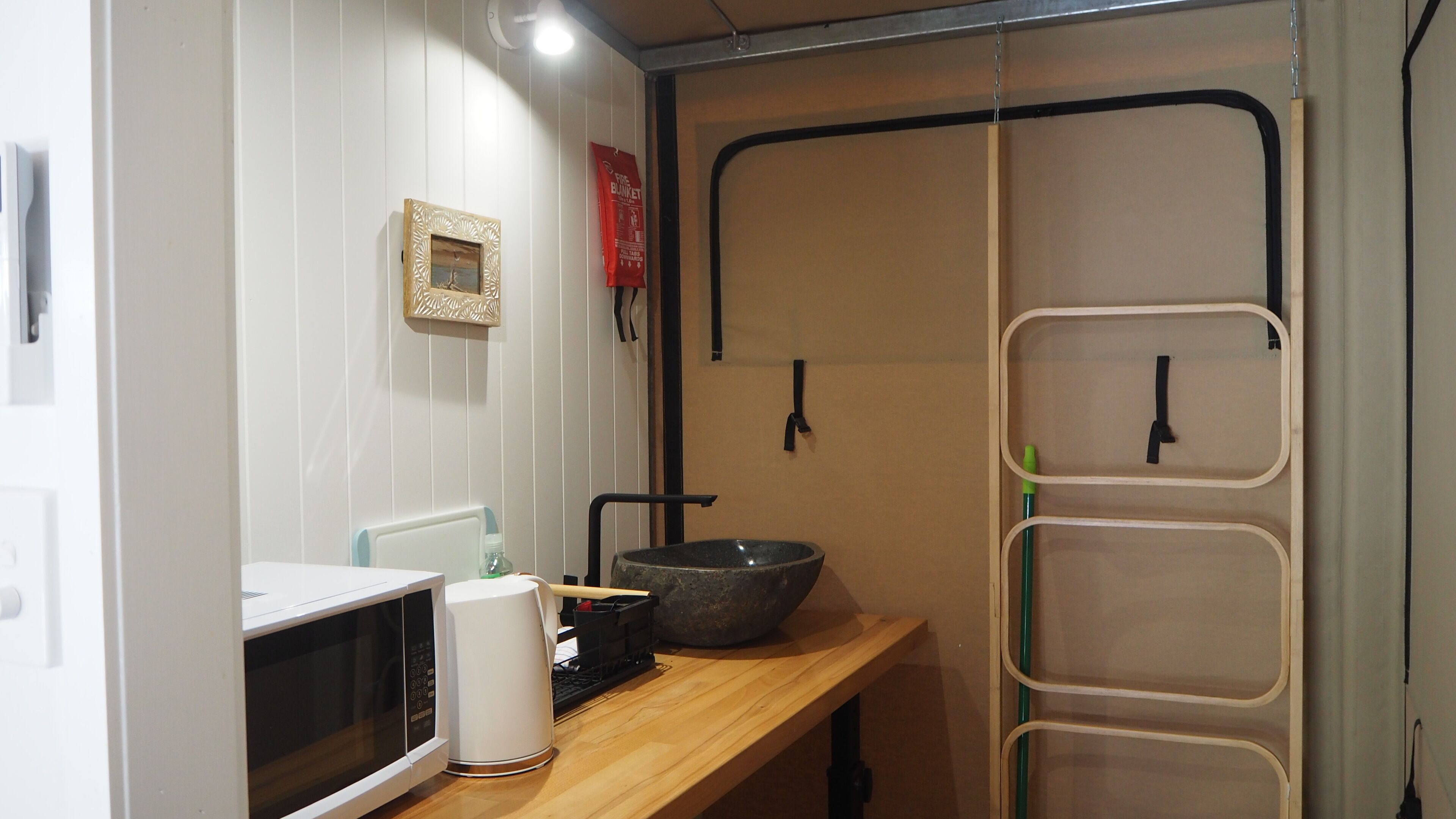 Una cocina compacta con microondas, un lavamanos y una encimera de madera.