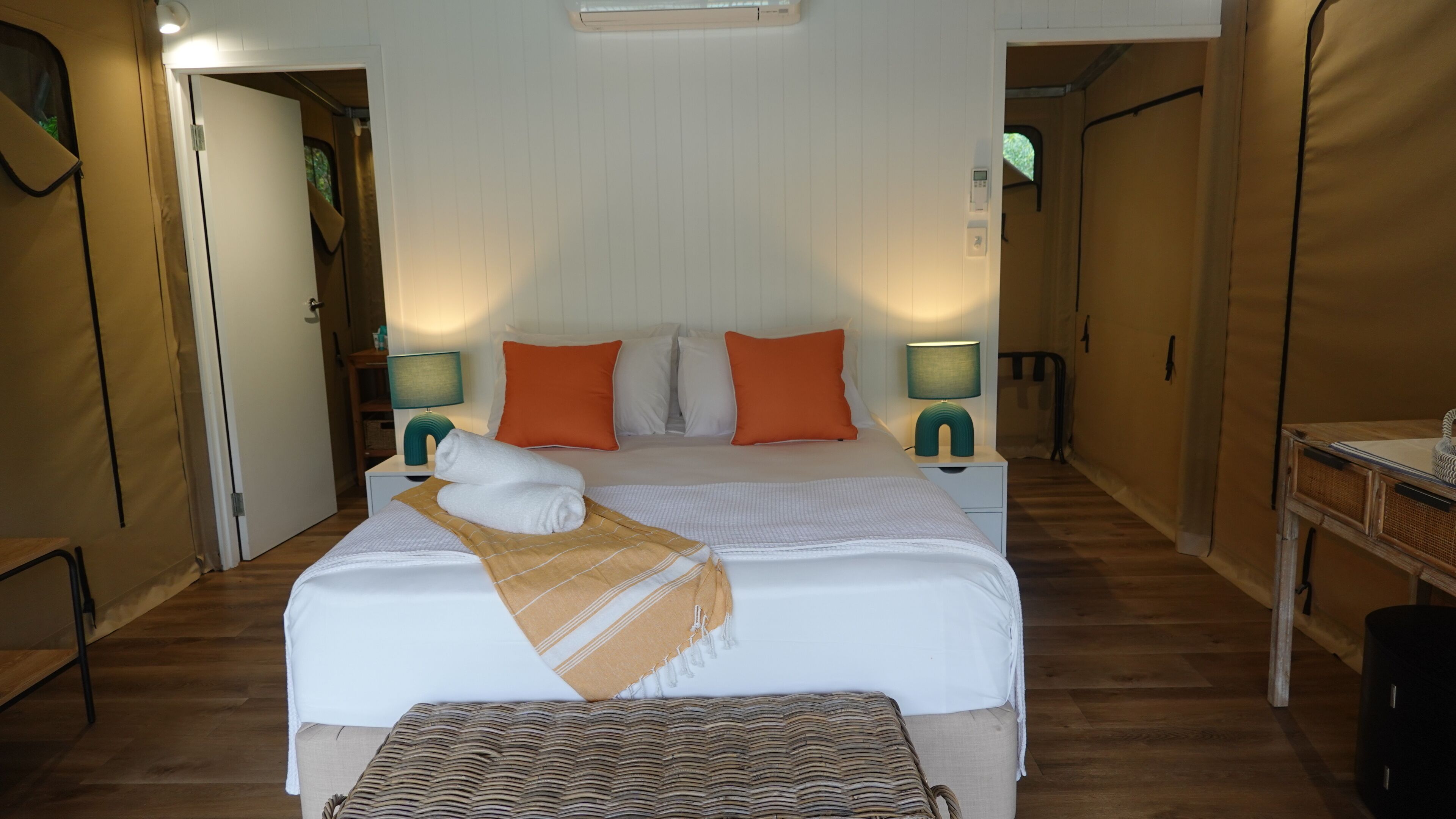 A bedroom with a bed, two nightstands, a bedside table, a lamp, and a window.