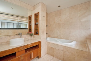 A modern bathroom with a large mirror, two sinks, a wooden vanity, and a bathtub. - Ocean Luxury Villa (Da Nang)