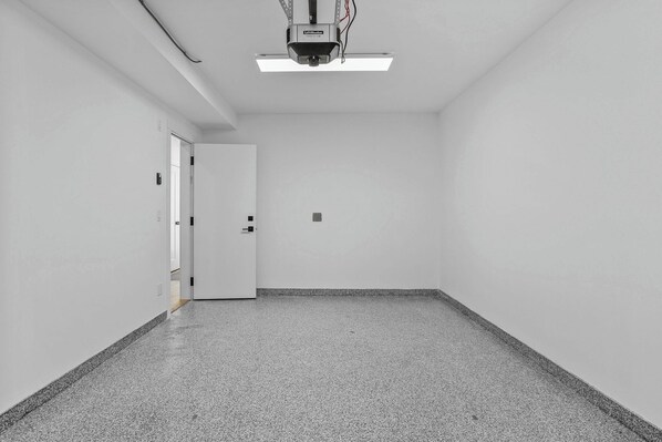 Un couloir avec un projecteur fixé au plafond, une porte et un sol à motifs.