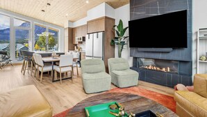 Una sala de estar moderna con chimenea, comedor y cocina.