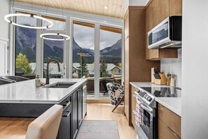 Une cuisine moderne dotée d’un grand îlot central, d’un four à micro-ondes et d’un four traditionnel.