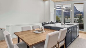 Una cocina moderna con una mesa de comedor de madera, sillas blancas y una isla grande con un lavamanos.
