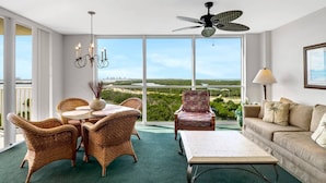 A spacious room with a balcony, wicker furniture, a ceiling fan, and a view of the landscape.